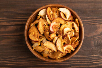 Dried Apples in wooden bowl on brown wooden. Top view, close up