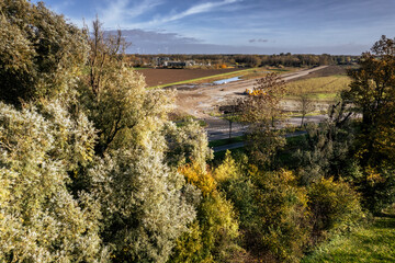 Scenic view of a developing landscape with autumn foliage and construction activity in the background near a rural area