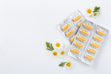 Fresh chamomiles with medicines on color background, top view