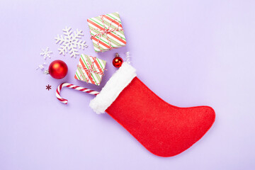 Christmas sock with gifts and decoration on color background, top view