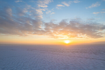 Vast, snow-covered frozen plain under a cloudy winter sky.