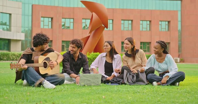 Indian young adult gen z male man group hold guitar play music lady woman group sing new song sitting garden park Happy relax girl boy team guy spend break time mood have fun joy enjoy good day place