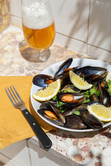 Traditional Spanish mussels dish with lemon and cold beer in sunny rustic outdoor setting