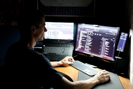 Skilled guy geek typing coding web development remote support security safety at modern home office work. IT specialist is programming. Remote work. Computer, laptop, IT industry.