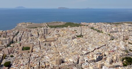 Aerial view of houses and buildings in the historic center of Marsala, in the province of Trapani, Sicily, Italy. In the background, on the horizon, are the Mediterranean Sea and the Aegadian Islands.