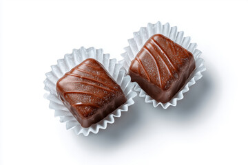 Two chocolate pralines in white paper wrappers on white background