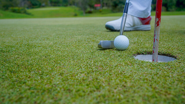Golfer putting ball on the green golf, lens flare on sun set evening time. - Powered by Adobe