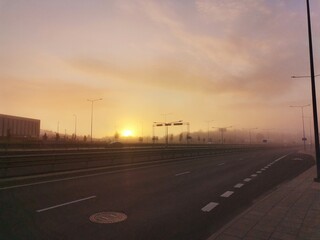 Fototapeta premium Orange dawn, seen from the road in an industrial area