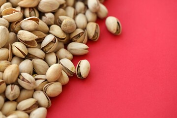 Tasty unpeeled pistachios on bright red background, top view flat lay background pattern