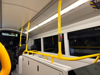 Inside a Manchester bus at night with bright yellow poles and modern seating