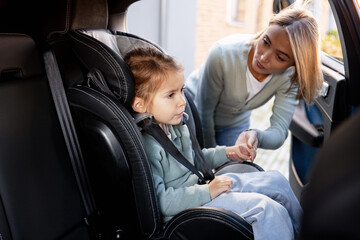 Mother securing child in car seat for safety