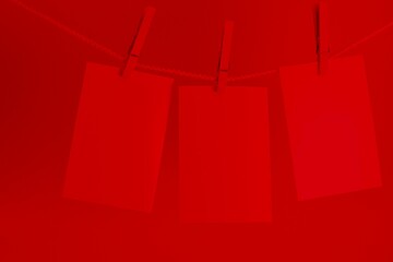 three photos hanging on a rope in the red light of a darkroom © Marshall