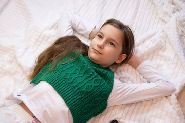 idea of ​​vacation, relaxation, and rest. A smiling girl lies on a white blanket. A child dreams.