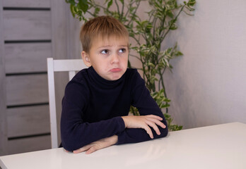 Naklejka premium concept of loneliness. Tired sad boy student sad at home . lonely little kid is upset and unhappy. Psychological trauma of child.