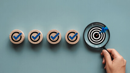 Five wooden circles with blue checkmarks and a magnifying glass over a target with an arrow tick