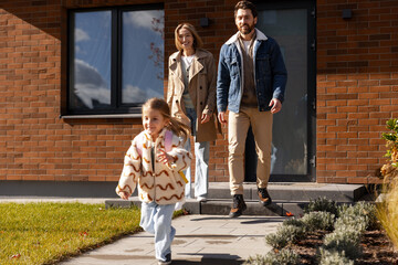 Happy family leaving modern house for school day