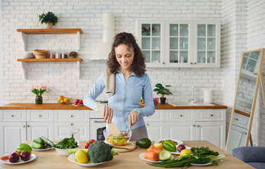 Woman preparing healthy meal, mixing colorful salad standing in home modern kitchen, fresh...