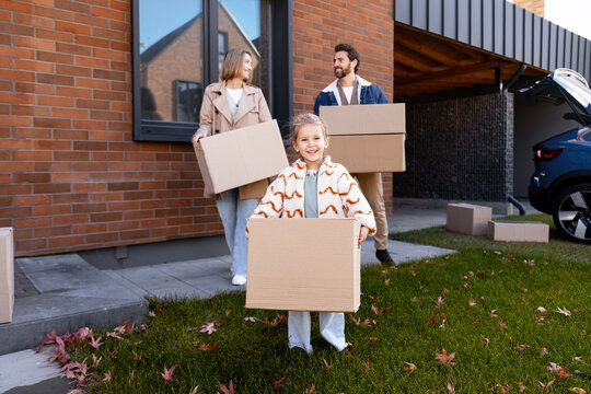 Happy family carrying boxes moving to new house