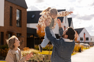Happy family playing outdoors in modern suburban neighborhood