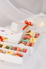 macaron dessert for christmas. homemade unique cookie. bow and sprinkles. various colors. present box. white