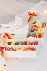 macaron dessert for christmas. homemade unique cookie. bow and sprinkles. various colors. present box. white