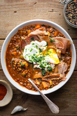 assiette de soupe de lentilles à la tomate, carottes, jambon cru grillé et oeuf poché