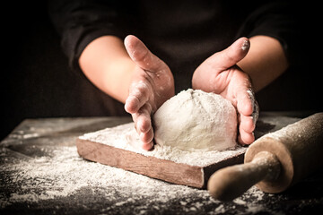 Image of a baker kneading dough. The flying dough creates a sense of movement and texture. Traditional baking concept. Homemade bread.