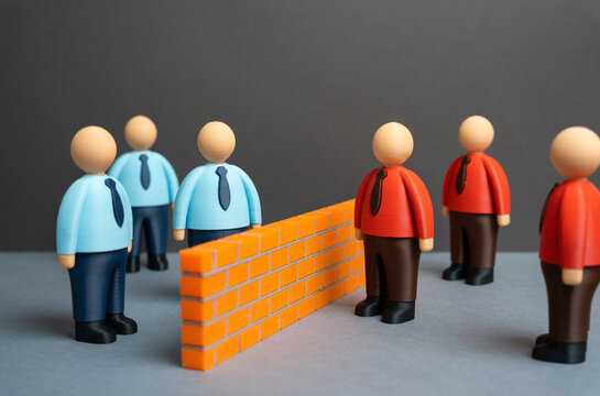 A brick wall separates two ideological camps of office workers. Two opposing teams or business departments. Competition, team disagreement, or workplace polarization.