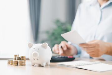 Concept of saving money and investment planning. A businesswoman drops coin into white piggy bank...