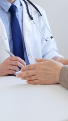 Doctor man taking notes while listening to a female patient explaining her symptoms during a...