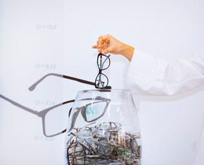 A doctor throws eyeglasses into a container at a medical center. Diagnosis of eye diseases. Concept: ophthalmology, vision health, vision diagnostics, medicine of the future.
