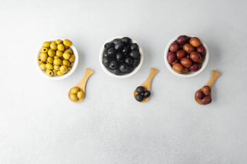 Assortment of green,  black and  kalamata  olives in bowls with wooden spoons