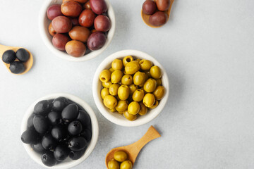 Variety of olives in bowls  on gray background, green olives, black and kalamata olives.