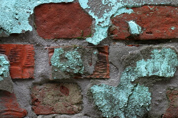 Background of a crumbling wall made of red clay brick and turquoise painted cement plaster