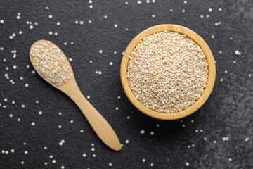 Quinoa seeds in wooden bowl and spoon with scattered grains