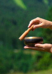 A woman holds a singing bowl in her hands. Selective focus.