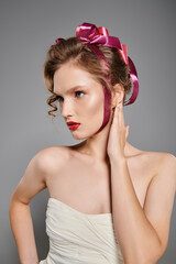 Naklejka premium Captivating young woman with elegant curls and a stylish pink ribbon in her hair