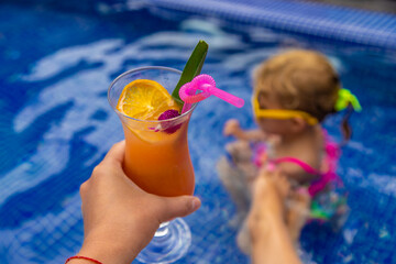 A woman in the pool drinks a cocktail. Selective focus.