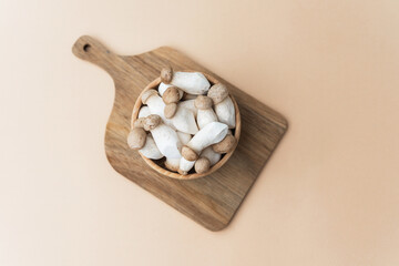 King oyster mushrooms in bowl on cutting board with beige background for natural product or recipe theme