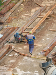 Construction Workers Among Reinforcement Bars and Heavy Equipment