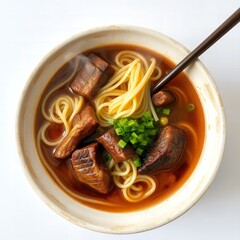 Close up view of a hearty bowl of beef noodle soup with tender chunks of meat and fresh green onions