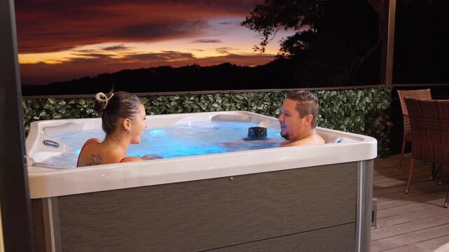Romantic couple enjoying a jacuzzi at sunset in an outdoor setting