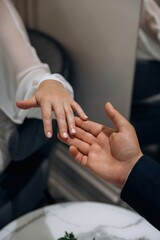 Close-up shot of a man's hand gently touching a woman's hand over a marble table, symbolizing connection, care, and support