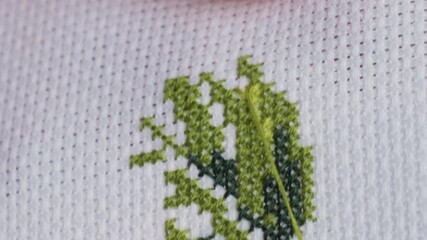extreme close up skilled crafter hand passing needle with green thread through cross stitch fabric, fingertip guiding neat x patterns, focused outdoor embroidery under soft daylight - Powered by Adobe