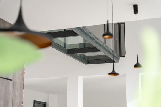 Pont en verre moderne &agrave; l&rsquo;int&eacute;rieur d&rsquo;une maison, reliant deux espaces et offrant une structure design transparente qui met en valeur la lumi&egrave;re et l&rsquo;architecture contemporaine.