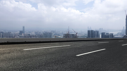 Urban road with cityscape in the background under cloudy sky