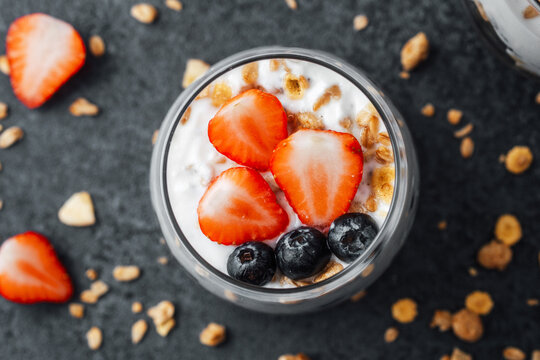 Yogurt granola parfait with strawberries and blueberries on  dark background