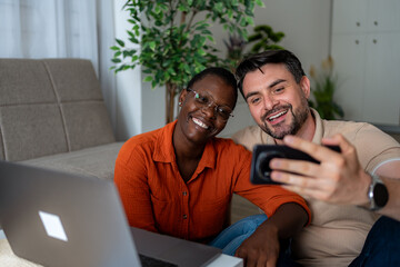 Couple sharing a joyful moment while looking at their phone at home in a cozy living room