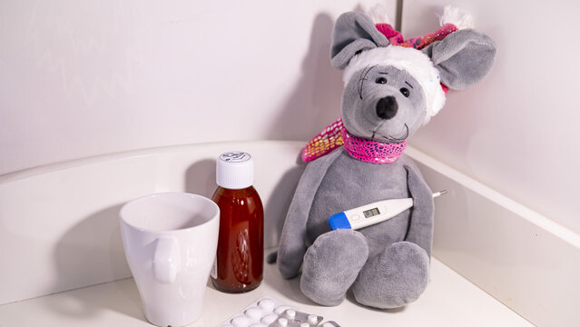 Seasonal flu concept for kids. Toy plush mouse with medical drugs and pills, medicines, thermometer.