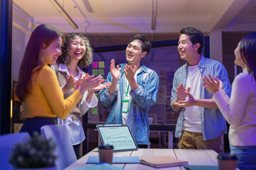 ibrant group of young startup professionals celebrate success during a late-night virtual meeting in a modern office, applauding with happiness and laughter. The confident team of AI-driven strategist